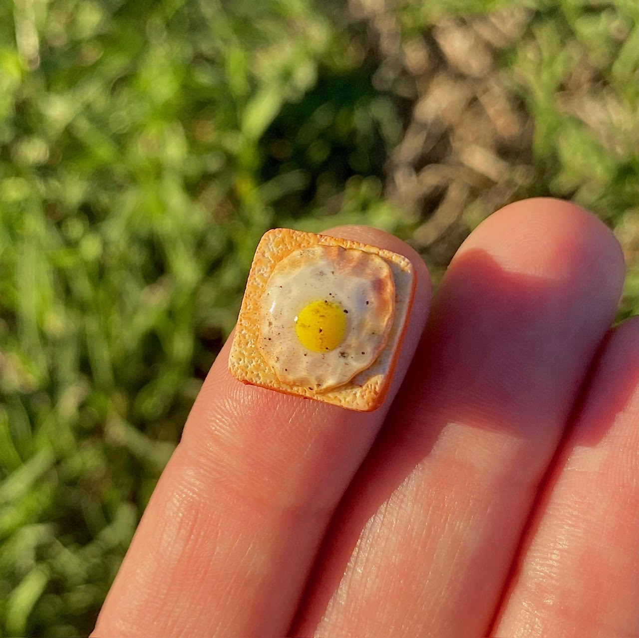 1/2 square inch miniature toast with fried egg on top topped with ground pepper.